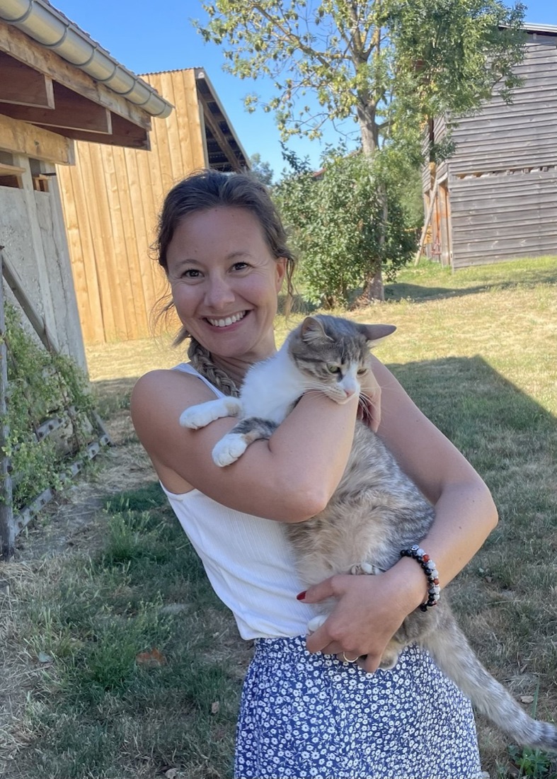 Célia, garde de chats à domicile, tenant un chat dans ses bras dans un jardin